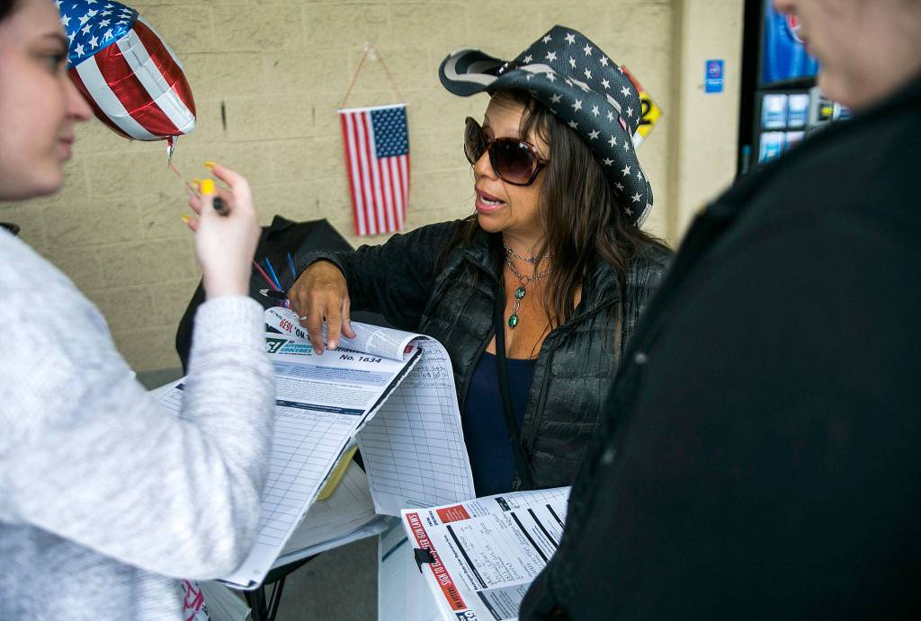 Lourdes Coria (center) helps a young woman register to vote outside of Walmart on June 27 in Everett. (Olivia Vanni / The Herald)