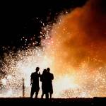 A trio in the lighting area at Boom City watches a shower of white-hot sparks from several fountains set off July 3, just as darkness falls. Story and video <a href="https://www.heraldnet.com/news/its-blast-when-everyone-gathers-at-boom-city/" target="_blank">here</a>. (Dan Bates / The Herald)