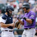The Rockies Noel Cuevas (right) celebrates as he reaches home after hitting a three-run home run in the seventh inning as Mariners catcher David Freitas looks on during a game on July 7, 2018, in Seattle. (AP Photo/John Froschauer)