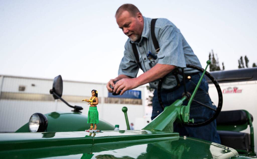 A hula girl statuette shakes as Jeff Newell looks for a place to mount a GoPro camera on his John Deere tractor July 11 in Arlington. Newell and Ron Wachholtz are driving their tractors to Prudhoe Bay, Alaska, and are raising money for the American Diabetes Association. (Andy Bronson / The Herald)