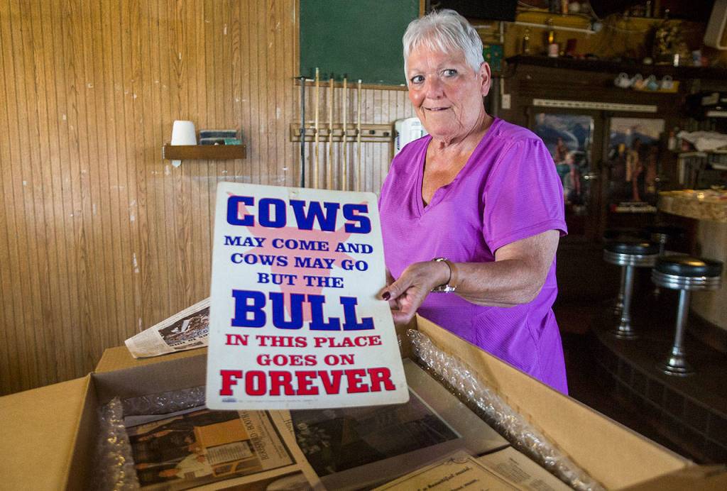 Audrey Young looks through a box of photos and mementos at Docs Pilchuck Tavern. (Olivia Vanni / The Herald)