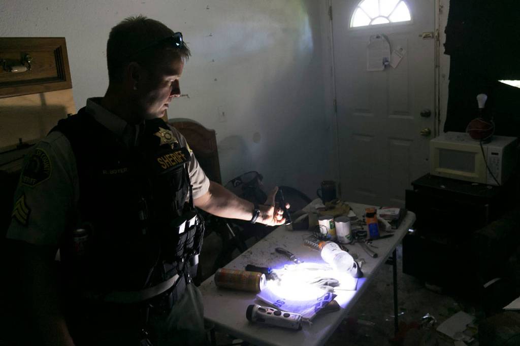 Snohomish County sheriffs Sgt. Ryan Boyer highlights living conditions of a nuisance house near Bothell July 11. (Kevin Clark / The Herald)