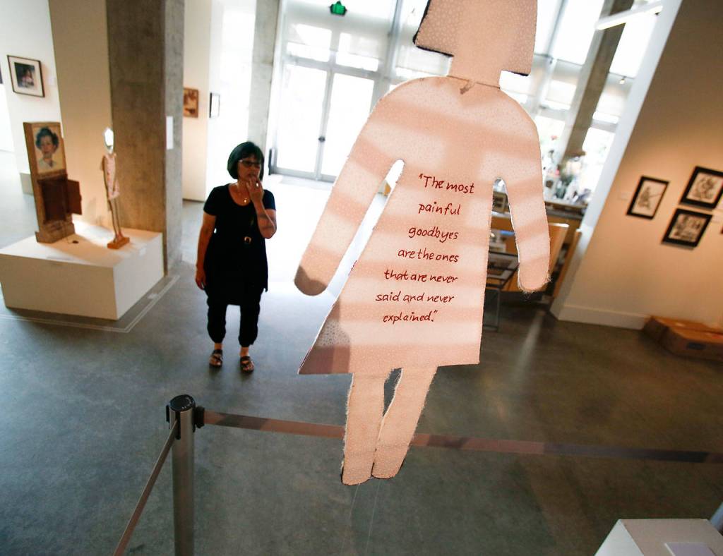 At the Schack Art Center, co-Artist of the Year Jan Hopkins looks over her Americans Interned artwork. (Dan Bates / The Herald)