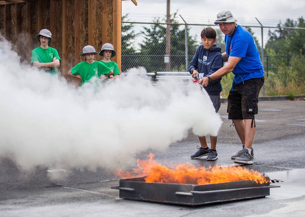 Max Williams, 12, learns how to use a fire extinguisher from Kevin Miller during Kids Fire Camp at South County Fire Administrative Headquarters on Wednesday in Everett. (Olivia Vanni / The Herald)