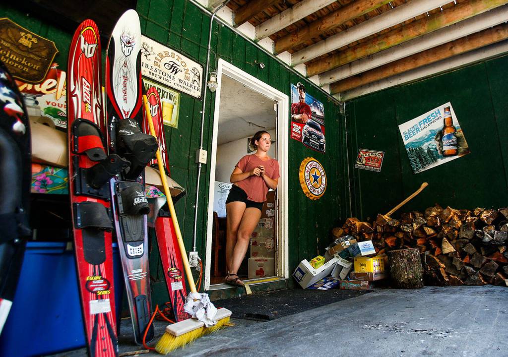 At the back door to the Lake Roesiger Store, owner Kevin Hicksons daughter, Rachel Hickson, 22, watches activity nearby. The covered back area serves as a beer garden and work space. She lives in the apartment above the store. (Dan Bates / The Herald)