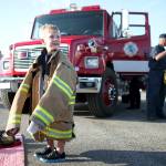 Donning a firefighting jacket, Wesson Fischer, then 4, smiles as he stands in front of a Camano Island fire engine during Stanwoods National Night Out in 2014. This years event is set for Aug. 7. (Herald file)