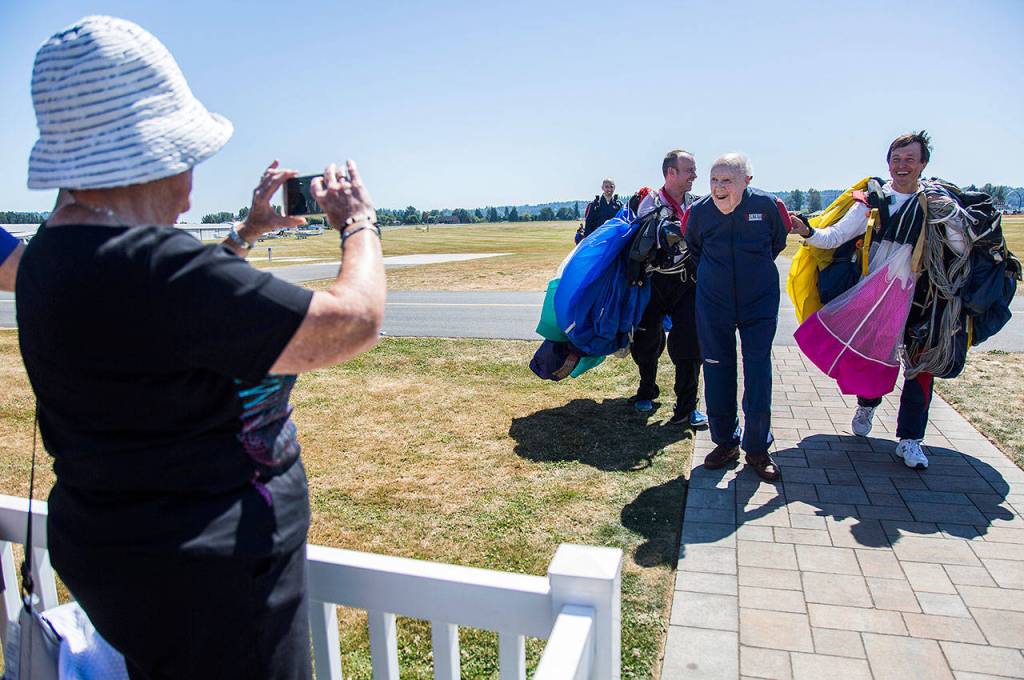 People take photos as Stu Williamson walks into the spectator area after his birthday skydive at Skydive Snohomish on Sunday. (Olivia Vanni / The Herald)