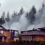 An aerial ladder from the Monroe Fire Department pours water on one of the three homes on the 2008 Street of Dreams that burned March 3, 2008. (Michael OLeary / Herald file)