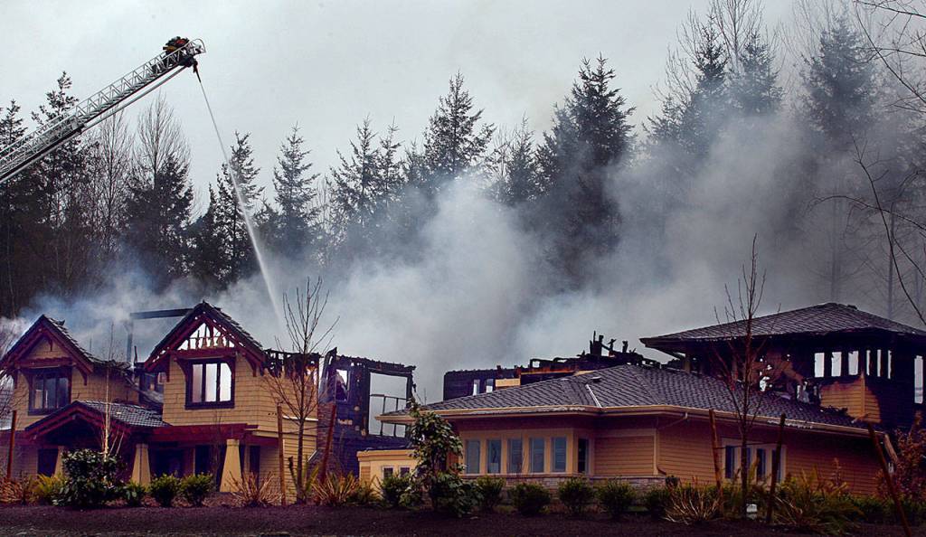 An aerial ladder from the Monroe Fire Department pours water on one of the three homes on the 2008 Street of Dreams that burned March 3, 2008. (Michael OLeary / Herald file)