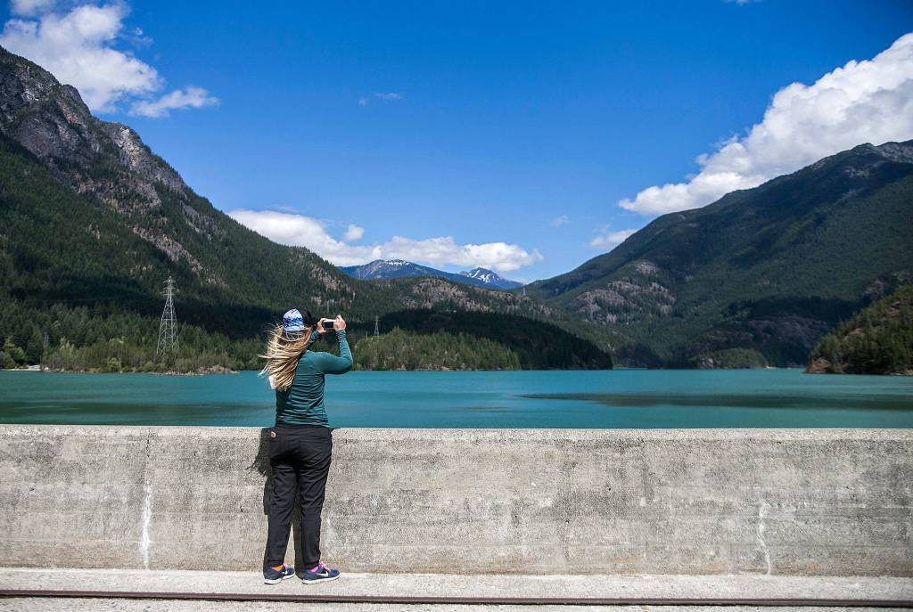 Danielle Phillips takes a photo of <a href="https://www.heraldnet.com/life/three-dams-two-lakes-and-mountains-all-around/" target="_blank">Diablo Lake from Diablo Dam</a> on June 26 in Rockport. (Olivia Vanni / The Herald)