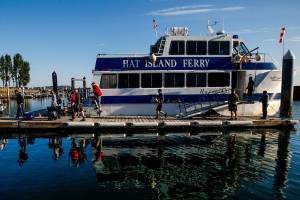 Arriving at Hat Island Marina early Thursday, islanders begin disembarking the Hat Island Ferry, which is called the Hat Express. At the top of the ramp stands Ray Brown, the captain. Below him on the dock are crew members Ryan Taisey, first mate (left) and Michael Jablinske. (Dan Bates / The Herald)