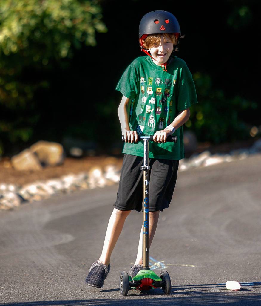 Outside the Marquart home in Woodway, Quintin Hall, 8, rides a scooter down a sloped driveway. (Dan Bates / The Herald)