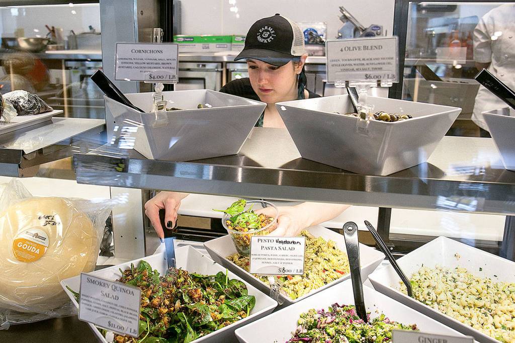 April Stair packages smokey quinoa salad at Farms & Market in Everett. (Kevin Clark / The Herald)