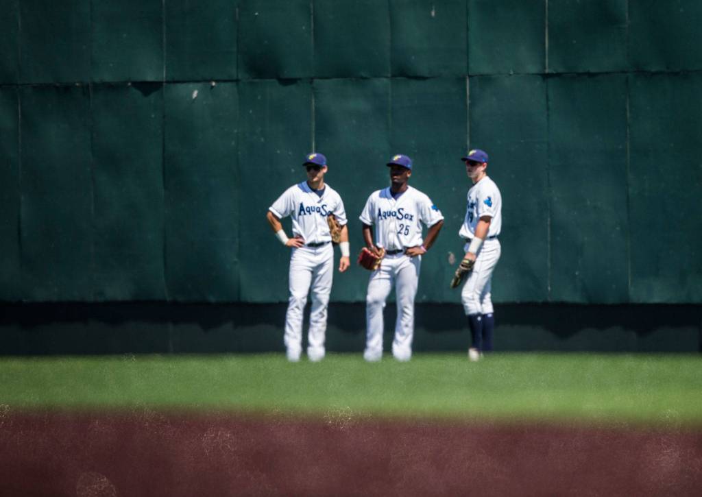 AquaSox outfielders stand together in the heat as the infielders have a meeting on the mound during the game against Vancouver at Everett Memorial Stadium on Thursday, July 26, 2018 in Everett, Wa. (Olivia Vanni / The Herald)