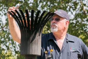 Steven Slawson lights a candle from the eternal flame Friday afternoon during the decommissioning of the Snohomish County Courthouse Veteran Memorial in Everett on July 27, 2018. (Kevin Clark / The Herald)