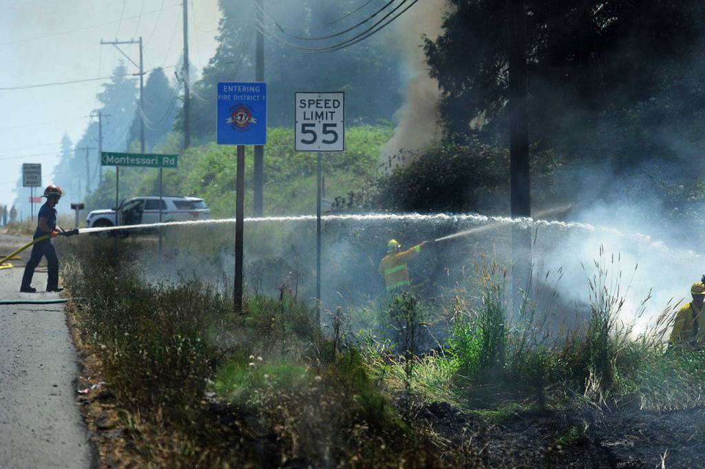 Firefighters from five fire districts worked to put out a fast spreading grass fire alongside Highway 9, just south of Snohomish, on Friday afternoon. (Doug Ramsay / For The Herald)