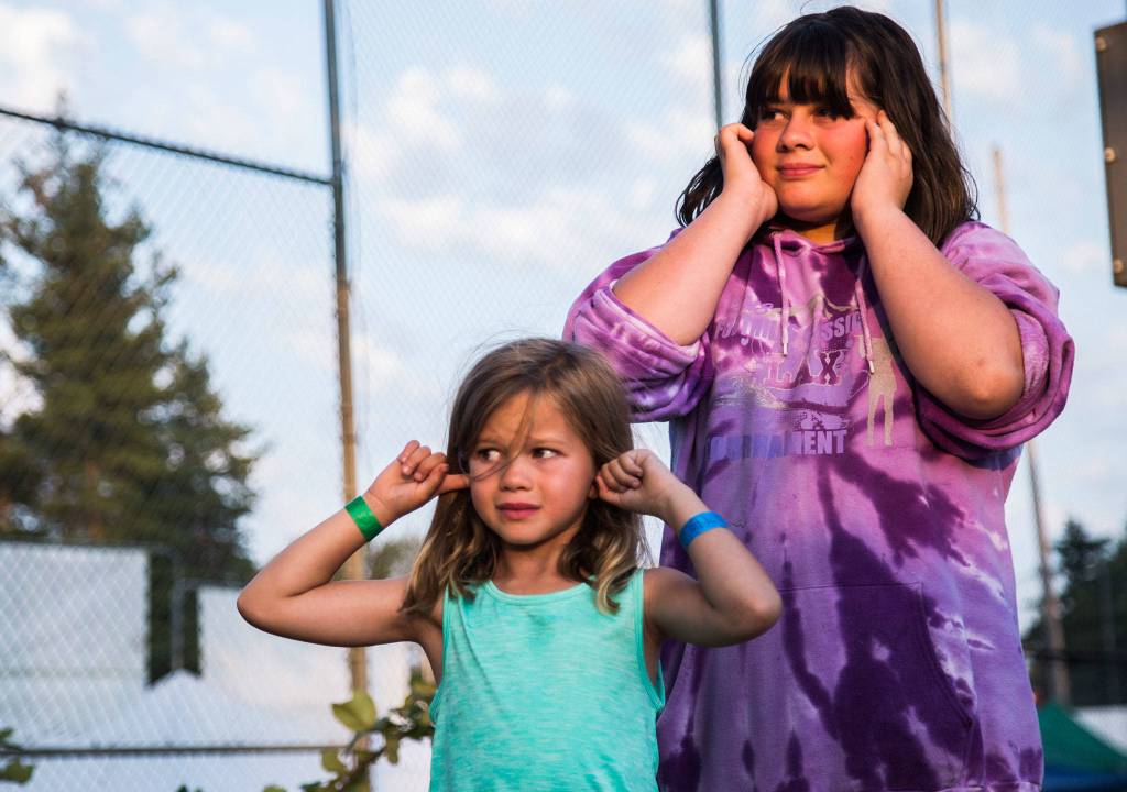 Hailey Larsen, 6, left, and sister Abbie Larsen plug their ears as the Safari Pirates light off one of their canons during the Tour de Terrace parade on Friday, July 27, 2018 in Mountlake Terrace, Wa. (Olivia Vanni / The Herald)