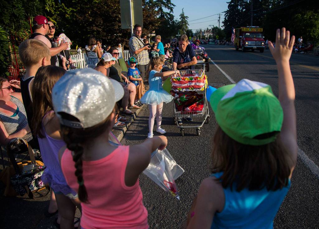 Children wave as candy is handed out during the Tour de Terrace parade on Friday, July 27, 2018 in Mountlake Terrace, Wa. (Olivia Vanni / The Herald)