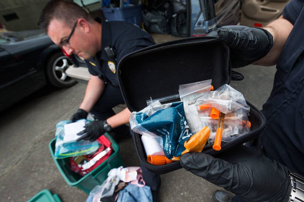 A heroin kit holds a half-full needle and other drug paraphernalia, as Monroe police officers search a car in the departments impound area on Thursday, June 14, 2018. (Andy Bronson / The Herald)