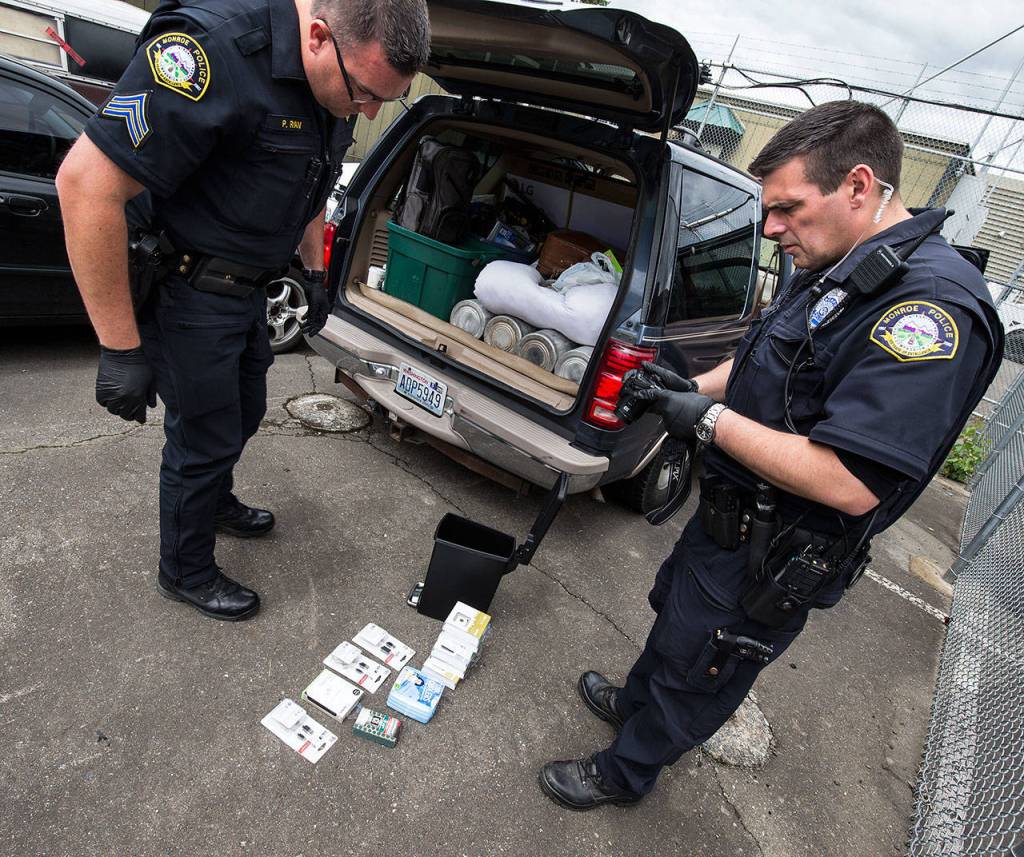 Monroe police officer Scott Kornish takes photos of stolen electronic items during a search of a vehicle, finding rip sheets, drugs and stolen items, in the departments impound area on Thursday, June 14, 2018. (Andy Bronson / The Herald)