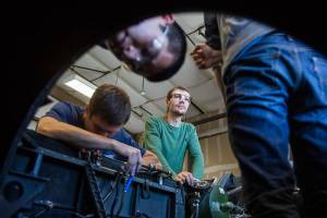 Alexey Ryabinin, center, looks up while his fellow classmates inspect the interior of a BAC Jet Provost that they removed a Viper engine from during class at Everett Community Colleges Aviation Maintenance Technician School on Friday, July 13, 2018 in Everett, Wa. (Olivia Vanni / The Herald)