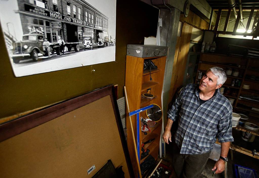 In a basement area of the old Everett Public Market, Chandler Williamson points out an old photo of the exterior taken from Grand Avenue. The building was completed in about 1915, Williamson said. (Dan Bates / The Herald)