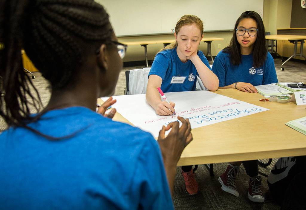 Alberta Gbla ( from left) talks with Aleksandra Kogalovski and Nina Huynh, of Mariner High School, during the Fred Hutch Pathway Research Explorers Program at the Fred Hutchinson Cancer Research Center on Aug. 9 in Seattle. (Olivia Vanni / The Herald)