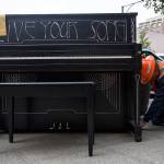 An Everett Public Works employee straps the Live Your Song piano into place in front of Major League Pizza in Everett on Aug. 1. (Olivia Vanni / The Herald)