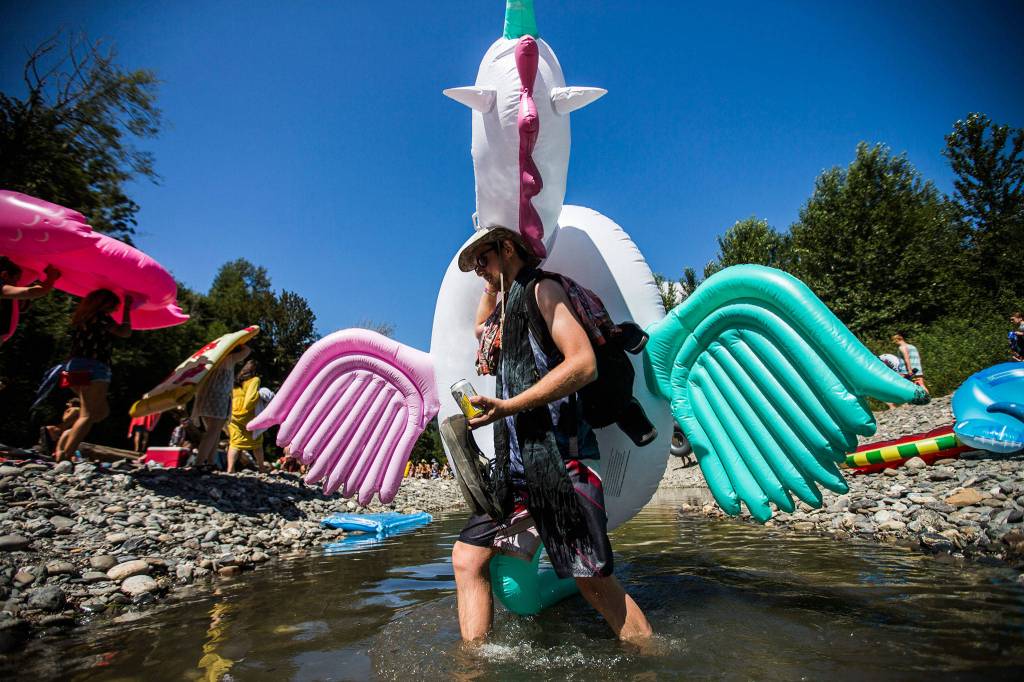 A unicorn float toy is carried across the river at the Summer Meltdown on Saturday, Aug. 4, 2018 in Darrington. (Olivia Vanni / The Herald)