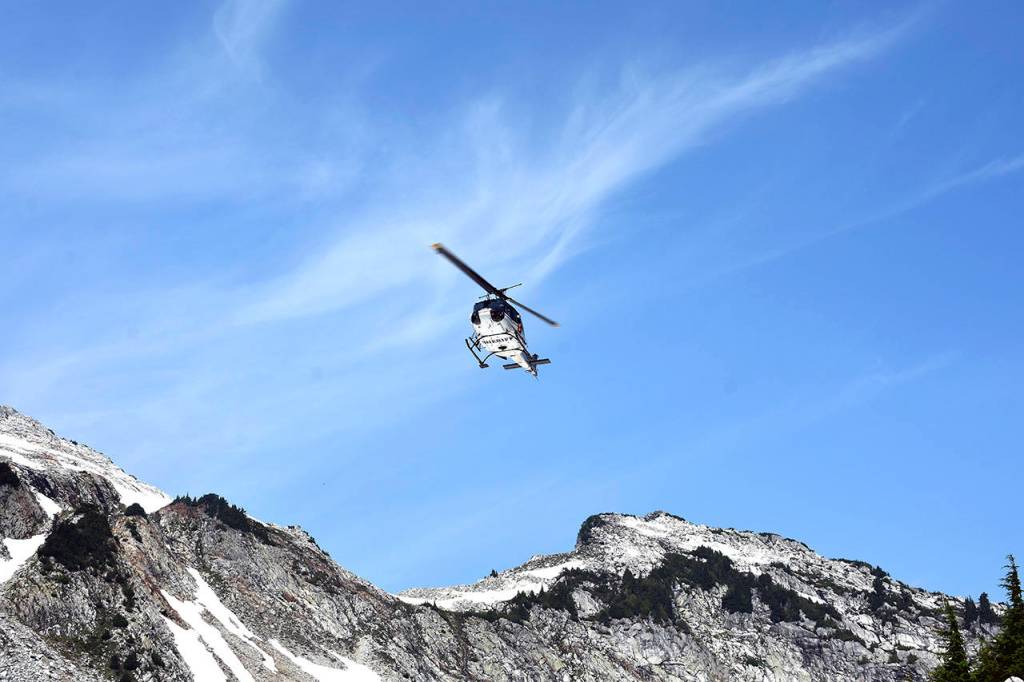 A helicopter crew scours rough terrain Sunday, Aug. 5, at Vesper Peak, in the search for missing hiker Sam Sayers, of Seattle. She went missing Aug. 1, on the hike about 30 miles east of Granite Falls. (Caleb Hutton / The Herald)