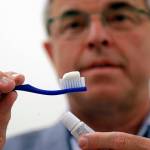 Philippe Hujoel, a dentist and University of Washington professor, holds a toothbrush and toothpaste as he poses for a photo in an office at the school in Seattle. (AP Photo/Elaine Thompson)