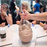 Kathleen Hodges (left), CJ Gray and Carole Scandella listen to instructions Friday as another Edmonds School District staffer uses an intranasal mucosal atomization device on a dummy head during ACT Training at Edmonds-Woodway High School. (Andy Bronson / The Herald)