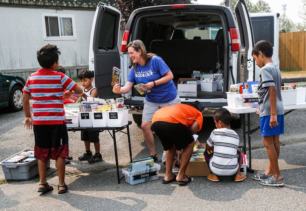 Rebekah Fox appears to find a good match between a young boy and a book Tuesday during the Book Cafes stop at the Snohomish Mobile Home Park. (Dan Bates / The Herald)