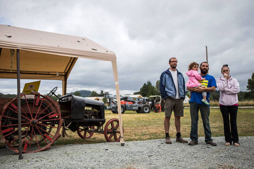 Dennis Morehouse, left, Raelyn Engbaum, Jason Engbaum and Tiffanie Engbaum look at the rubble left from the barn that caught fire at the Sky Valley Stock and Antique Tractor Show grounds on Saturday, Aug. 11 in Monroe. (Olivia Vanni / The Herald)