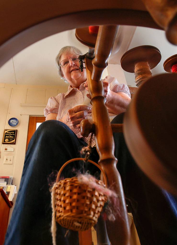 Elaine Wilson creates fine wool yarn on her spinning wheel at one end of the kitchen. (Dan Bates / The Herald)