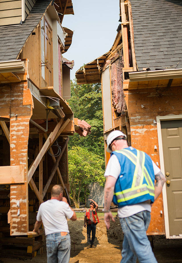 Casjen Cramer, of Nickel Bros., looks up to see how the main house lines up with the garage structure during the moving of a house Wednesday on Bellflower Road in Bothell. (Olivia Vanni / The Herald)