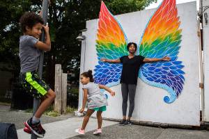 Lindsey T.H. Jackson, right, and her children, Cohen, 6, left, and Taylor, 4, center, pose for pictures in front of the butterfly wing art installation in Langley. (Olivia Vanni / The Herald)