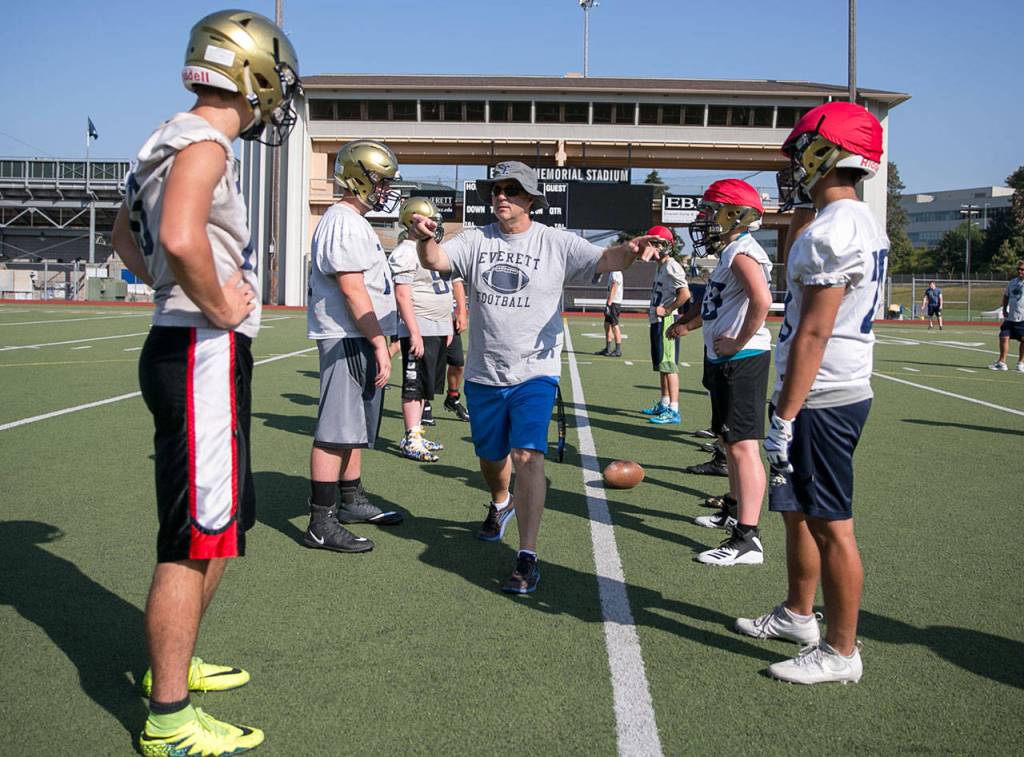 Everett coach David Coldiron walks the line of scrimmage during practice on Aug. 17, 2018, at Everett Memorial Stadium. (Kevin Clark / The Herald)