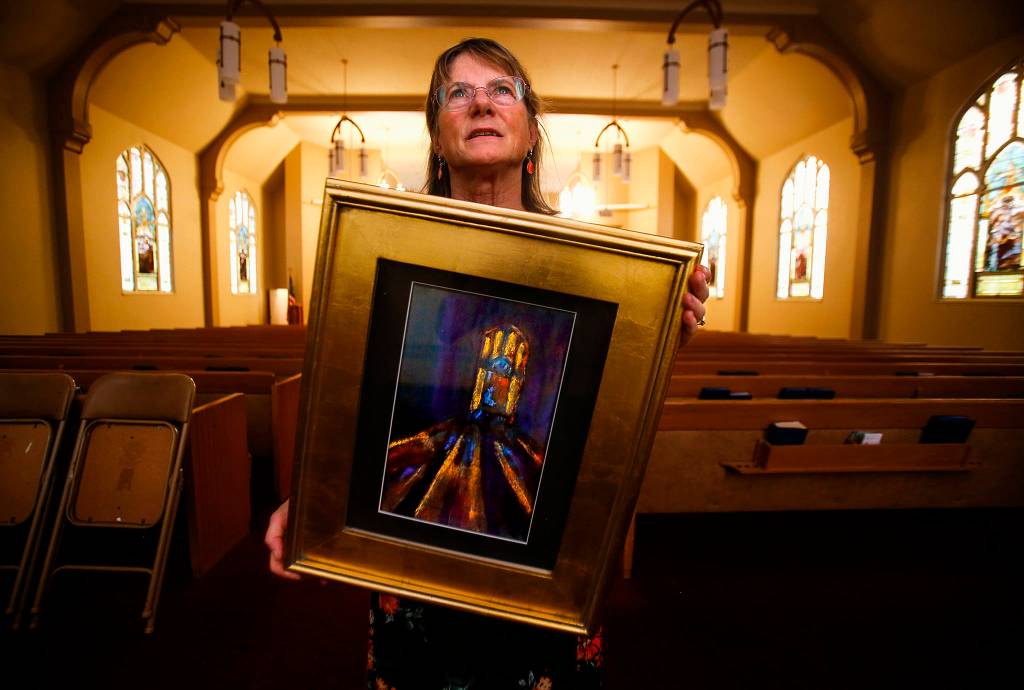 Artist Laurie Povey Crawford holds one of several paintings she created for the Everett Art Walk. Crawford lived in Everett 45 years before learning from a Herald article that the stained glass windows at First Presbyterian Church had been created in 1910 by the Povey Brothers Studio, her great-grandfathers business in Portland. See the windows and read her story <a href="https://www.heraldnet.com/news/stained-glass-windows-offer-glimpse-of-history-philanthropy/" target="_blank">here</a>. (Dan Bates / The Herald)
