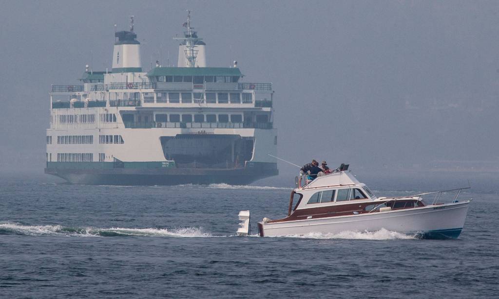 A boat passes by as the Washington State ferry Tokitae heads into smog, on its way to the Clinton ferry dock, Aug. 20 in Mukilteo. (Andy Bronson / The Herald)