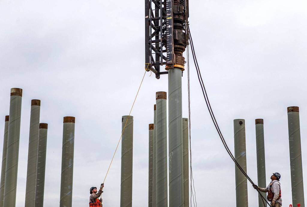 Two workers align the pile driver during <a href="https://www.heraldnet.com/business/dont-worry-that-pile-drivers-limited-to-2000-clunks-a-day/" target="_blank">construction</a> at the Port of Everett on Aug. 17 in Everett. (Olivia Vanni / The Herald)