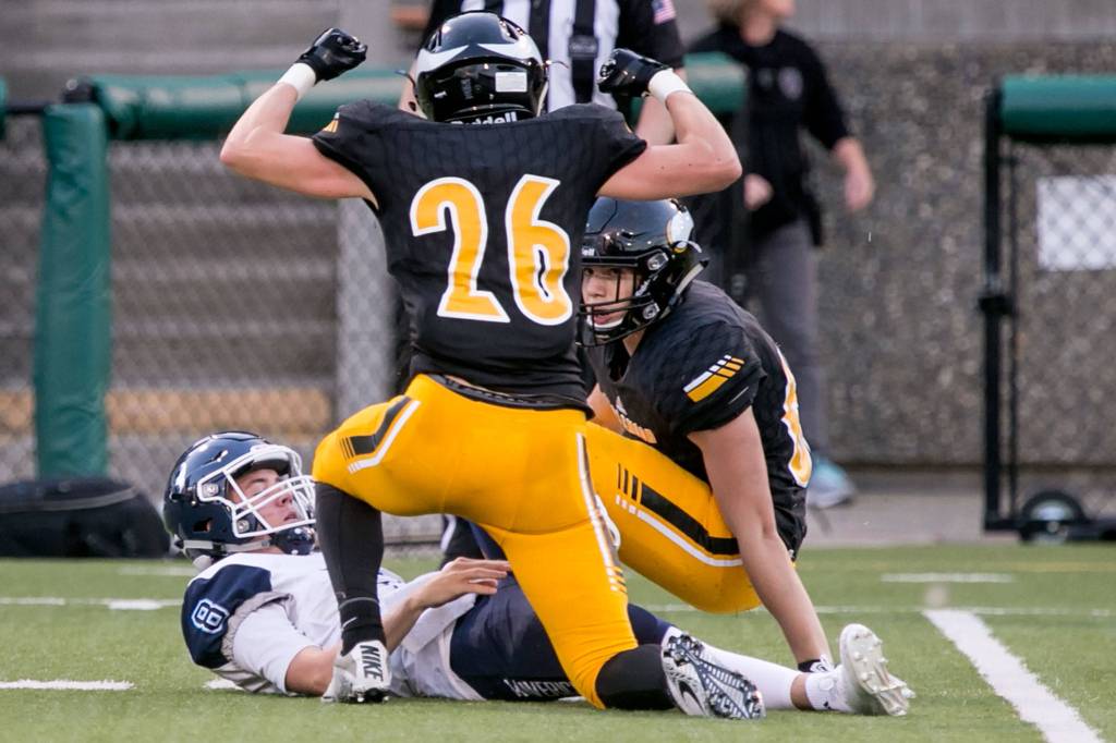 Inglemoors Ethan Noll celebrates his sack of Meadowdales Hunter Moen (left) and Inglemoors Chase Ingersoll (right) looking on Thursday night at Pop Kenney Stadium in Bothell on August 30, 2018. Inglemoor won 29-28. (Kevin Clark / The Herald)