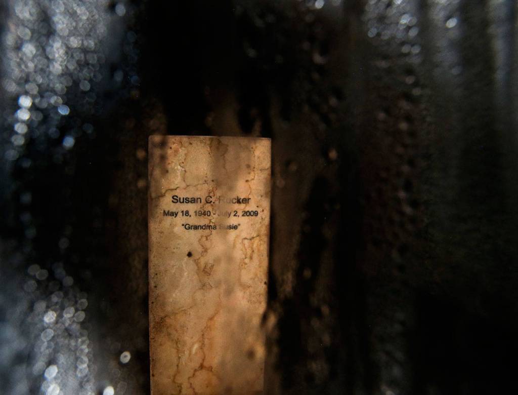 A small amount of filtered light finds its way to the urn of Susan Rucker behind protective glass. (Dan Bates / The Herald)