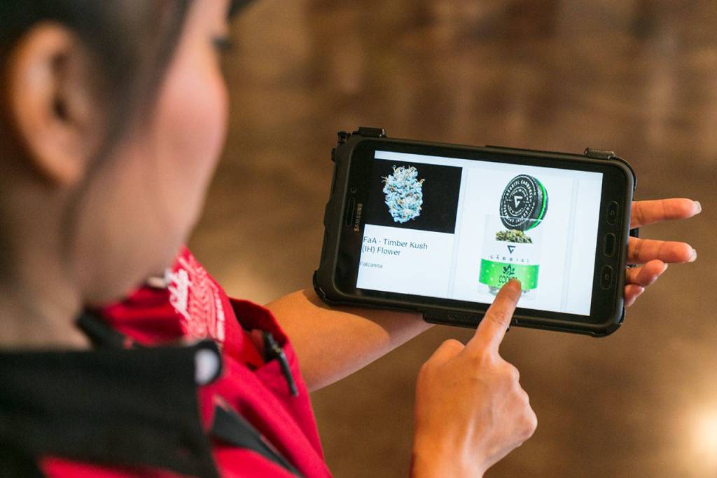 Wiyanna Benally demonstrates the tablets used by staffers at Tulalip Remedy. (Kevin Clark / The Herald)