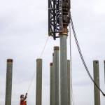 Two workers align the pile driver the pile during construction at the Port of Everett on Aug. 17, 2018 in Everett, Wa. (Olivia Vanni / The Herald)
