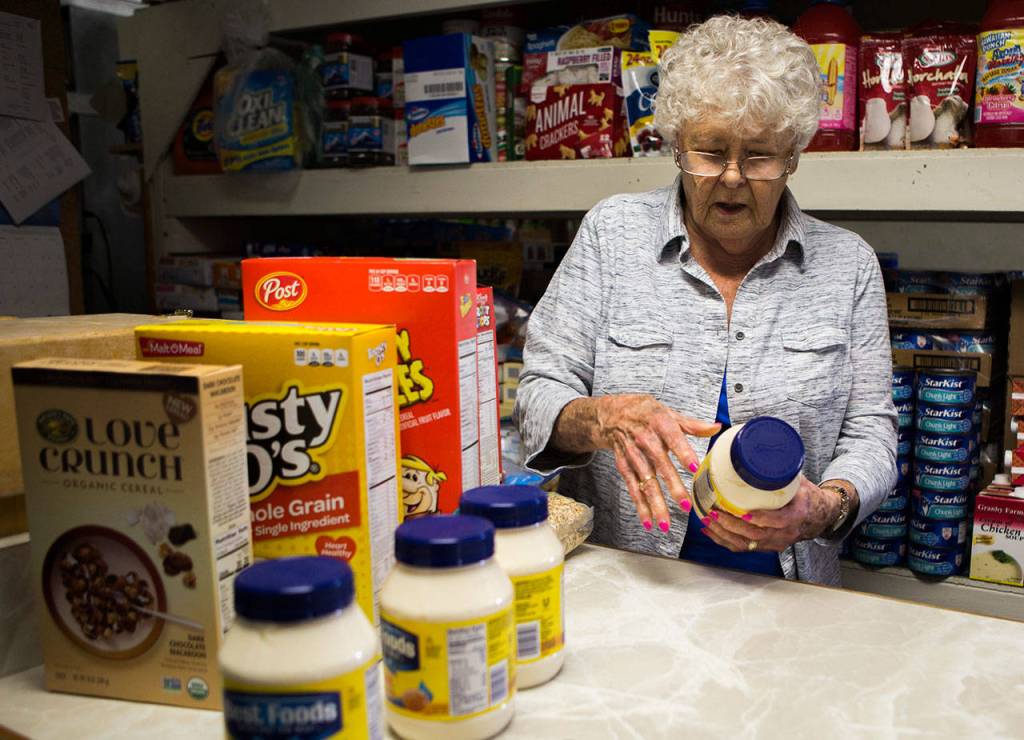 Marj Zehrung places food out on the counter before customers walk into the Lake Stevens Community Food Bank on Aug. 30 in Lake Stevens. (Olivia Vanni / The Herald)