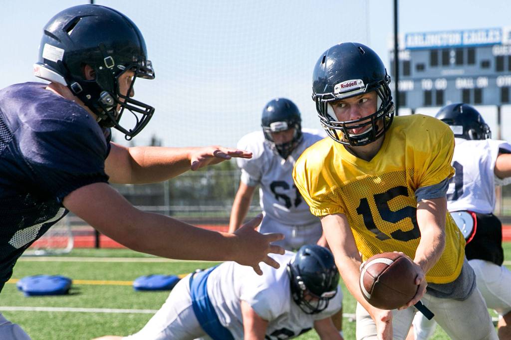 Anthony Whitis (right) hands off to Kirahy Meyers during practice at Arlington High School on Aug. 27. (Kevin Clark / The Herald)