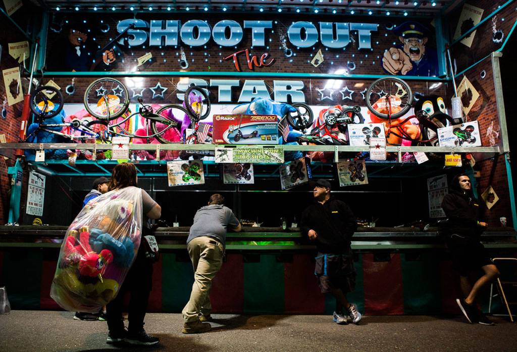 A girl with a bag full of prizes watches as friend plays the Shoot Out The Star game at the Evergreen State Fair on Sept. 1, 2018 in Monroe, Wa. (Olivia Vanni / The Herald)