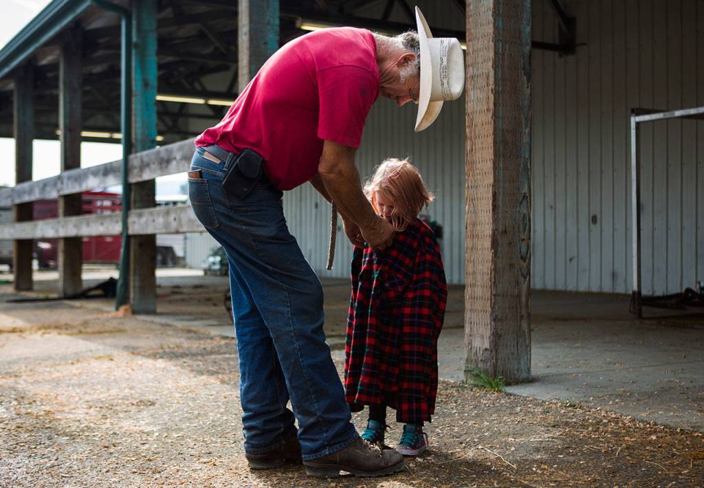 John Gearhart helps his granddaughter Sophie Richards, 4, button up an oversized flannel at the Evergreen State Fair on Aug. 29, 2018 in Monroe, Wa. (Olivia Vanni / The Herald)