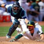 Oaklands Matt Joyce slides underneath the tag of Seattle catcher Mike Zunino in the sixth inning of Sundays game in Oakland, California. Joyce scored on a single by Marcus Semien. (AP Photo/Ben Margot)